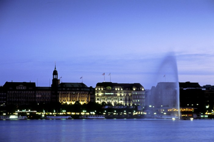 Blick auf die abendliche, hell erleuchtete Binnenalster und den Jungfernstieg; im Vordergrund die Alsterfontaine