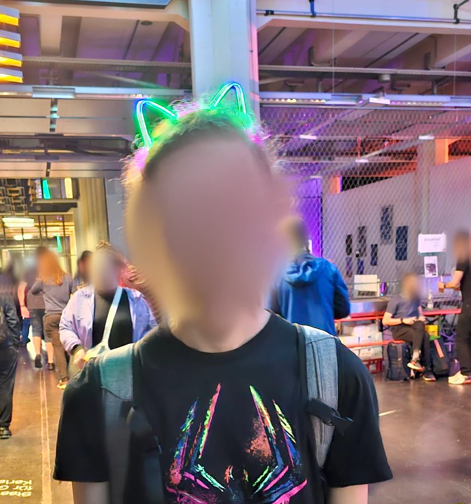 A person wearing colorful lit-up catears. All faces in the image are blured.